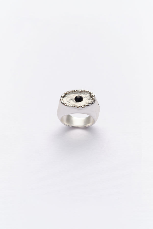 A vintage silver ring with a black cabochon centerpiece, surrounded by a circular design with small silver accents.