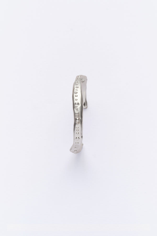 A silver cuff bracelet with a vintage look, displayed against a white background.