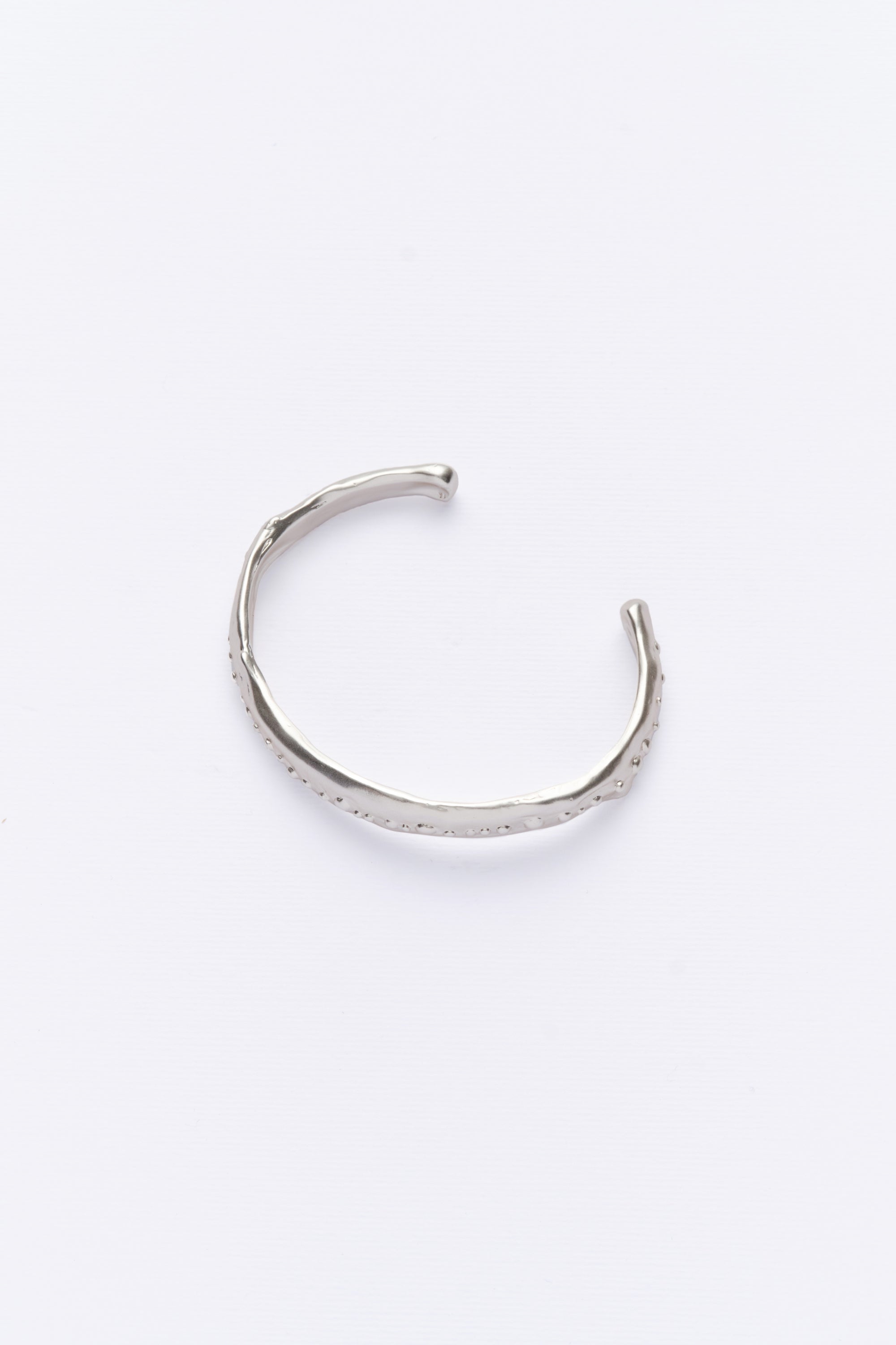 A silver-colored cuff bracelet with a vintage look, displayed against a white background.