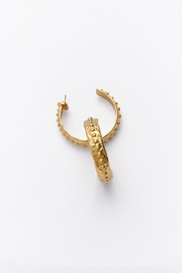 Close-up of gold textured hoop earrings with beaded detailing
