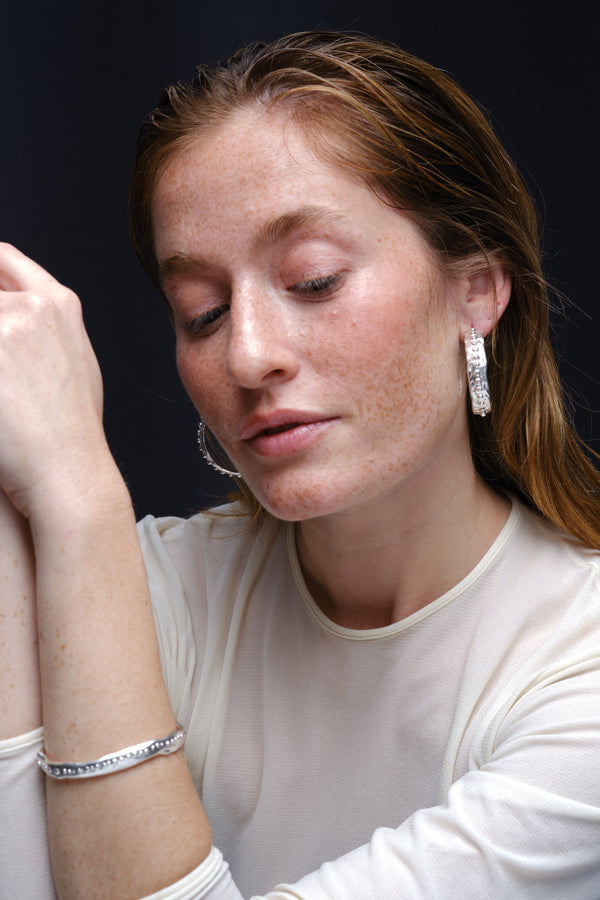 Silver textured hoop earrings and bracelet worn on model