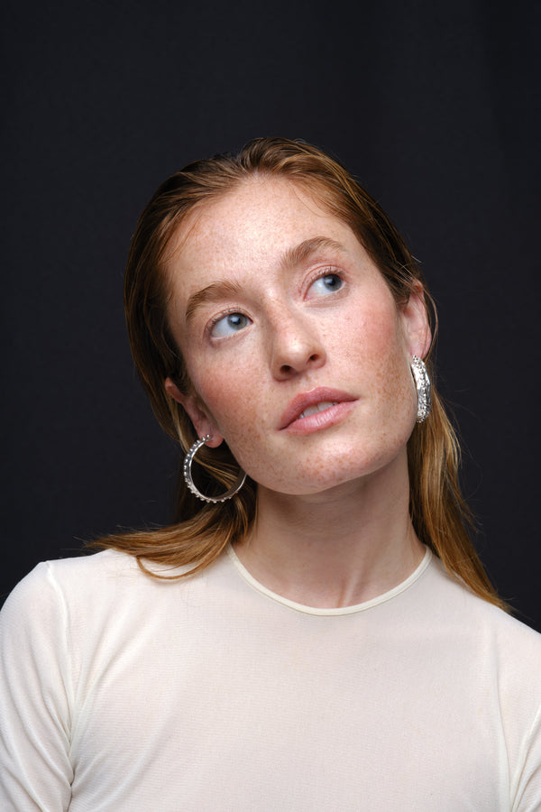 Silver textured hoop earrings worn on model portrait