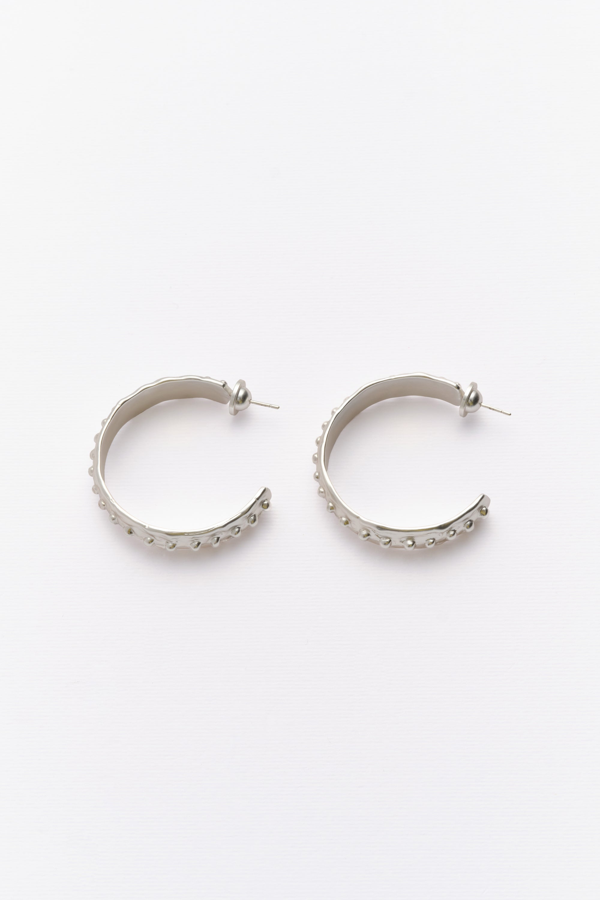 Silver textured hoop earrings with beaded edge flat lay