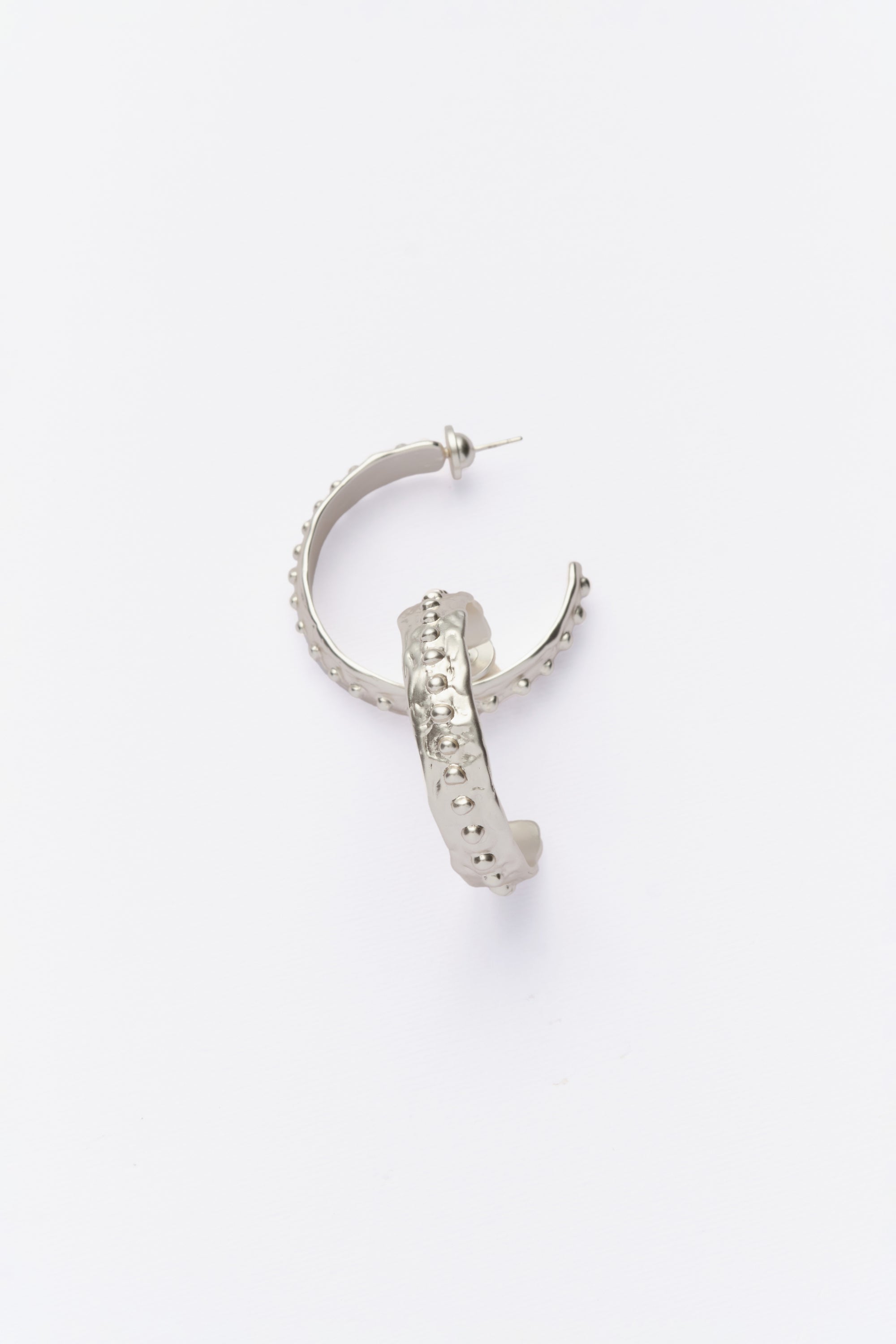 Close-up of silver textured hoop earrings with beaded detailing