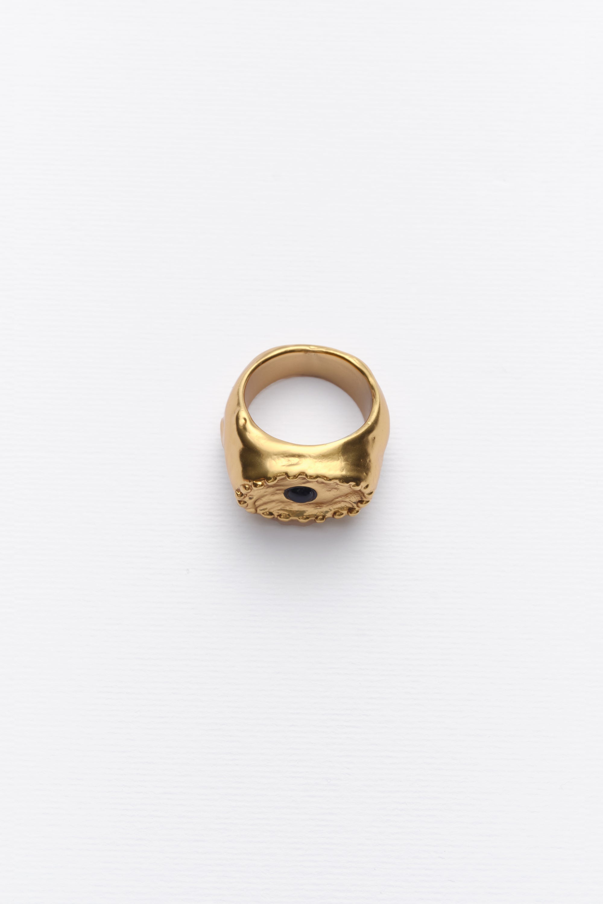 A vintage gold ring with a black cabochon in the center, featuring a textured band on a white background.