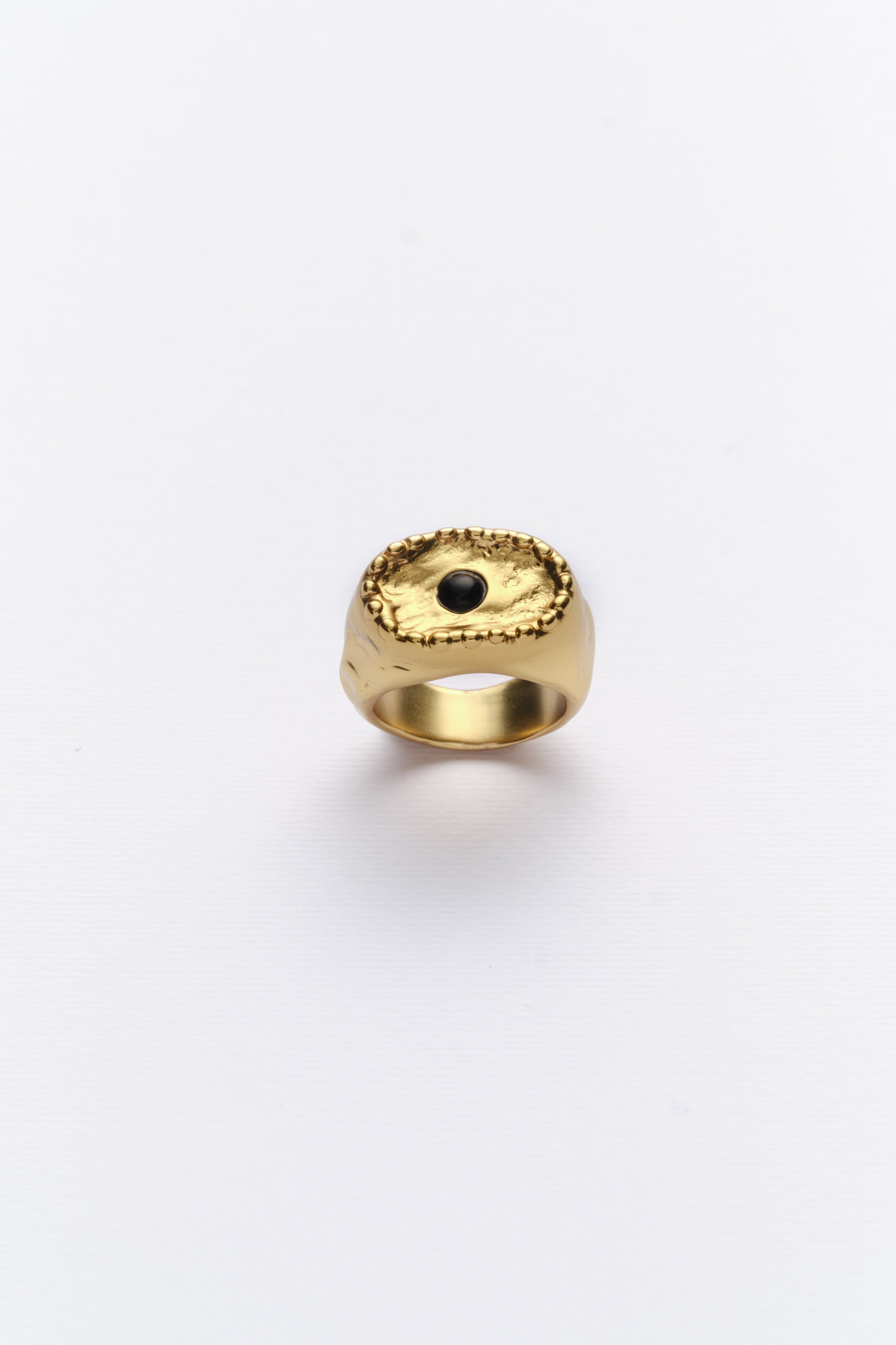 A vintage gold ring with a black cabochon in the center, featuring a textured band on a white background.