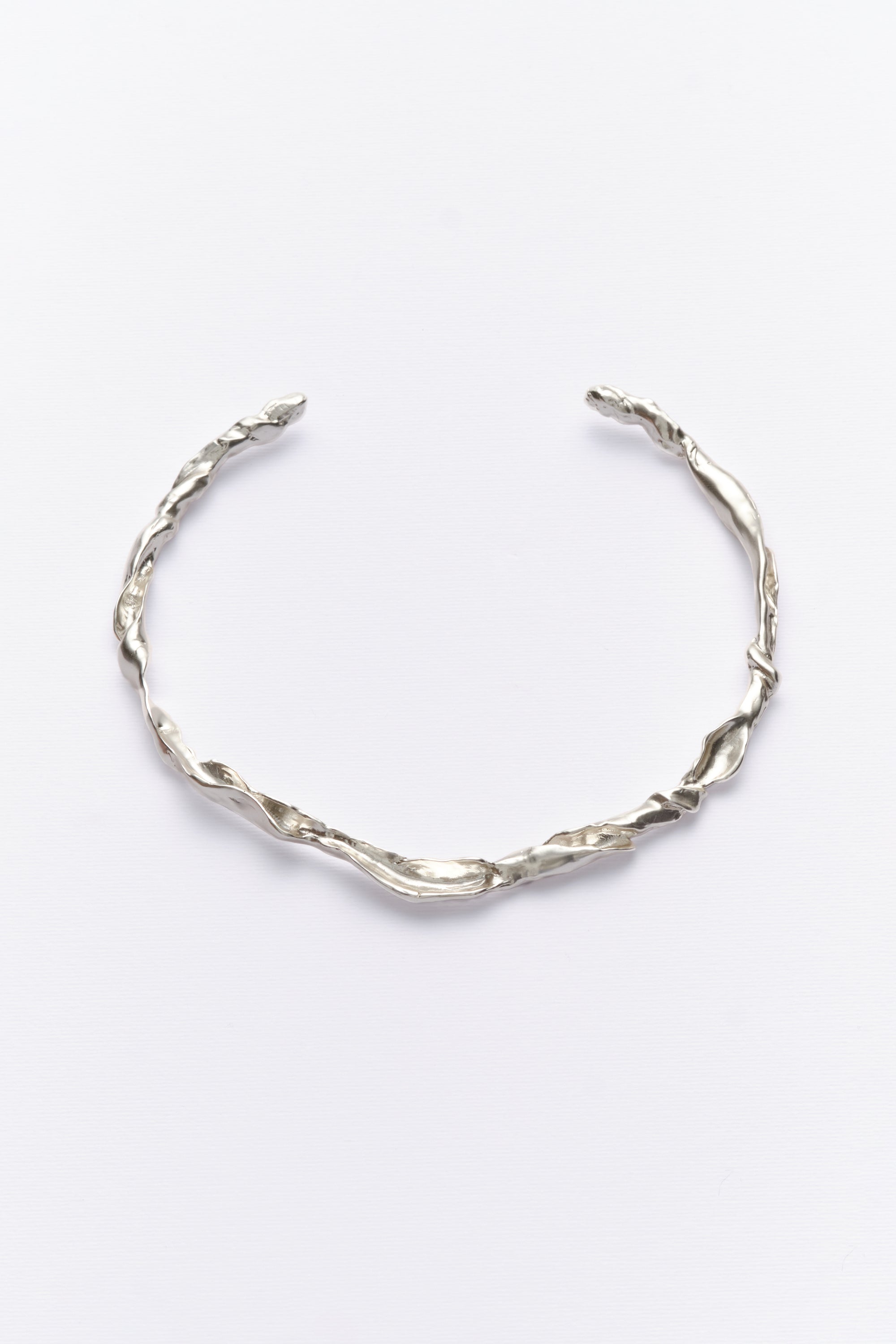 A silver choker necklace with an adjustable open side, displaying a textured design resembling tree skin.