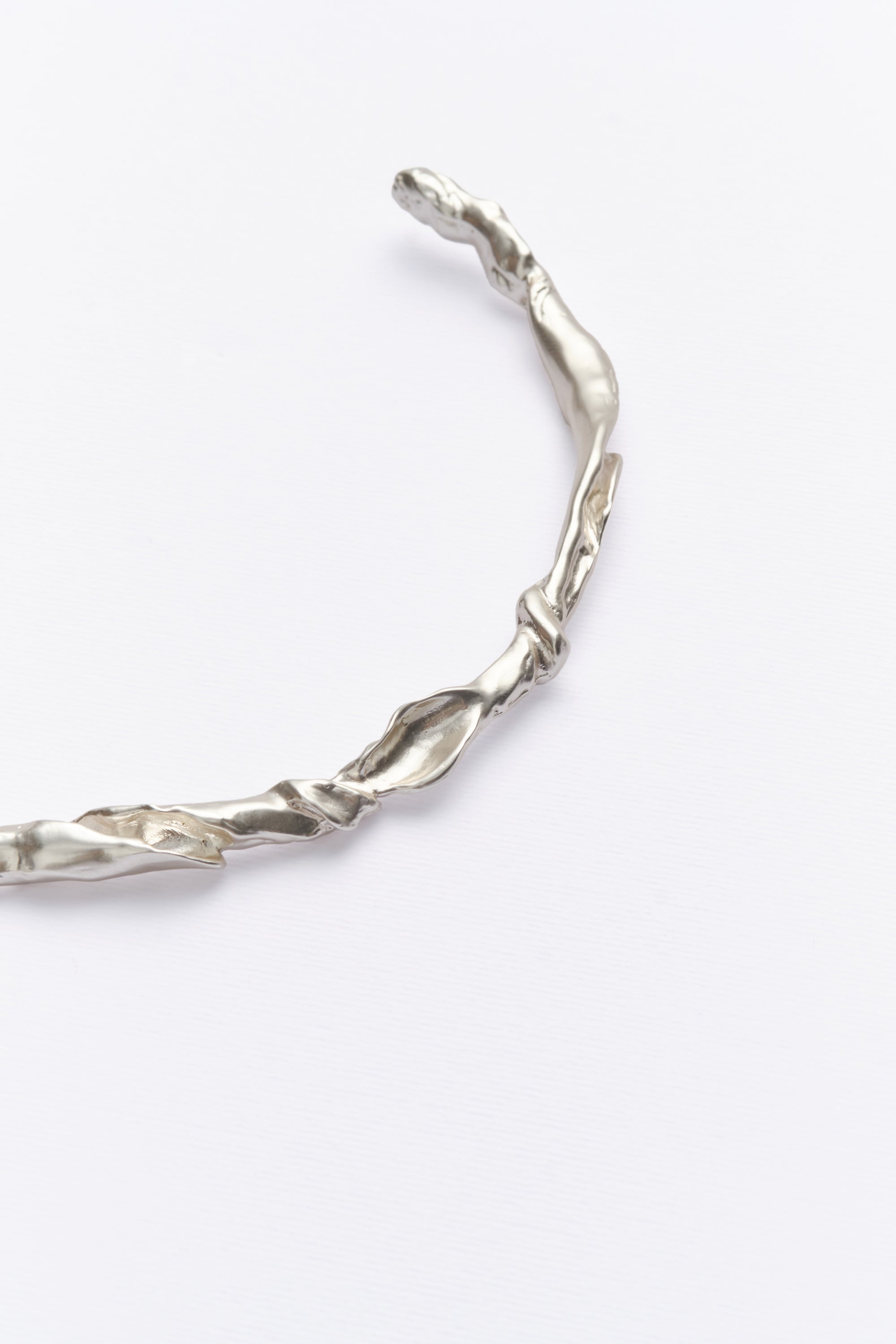 Minimalist textured silver choker with organic sculptural design on white background