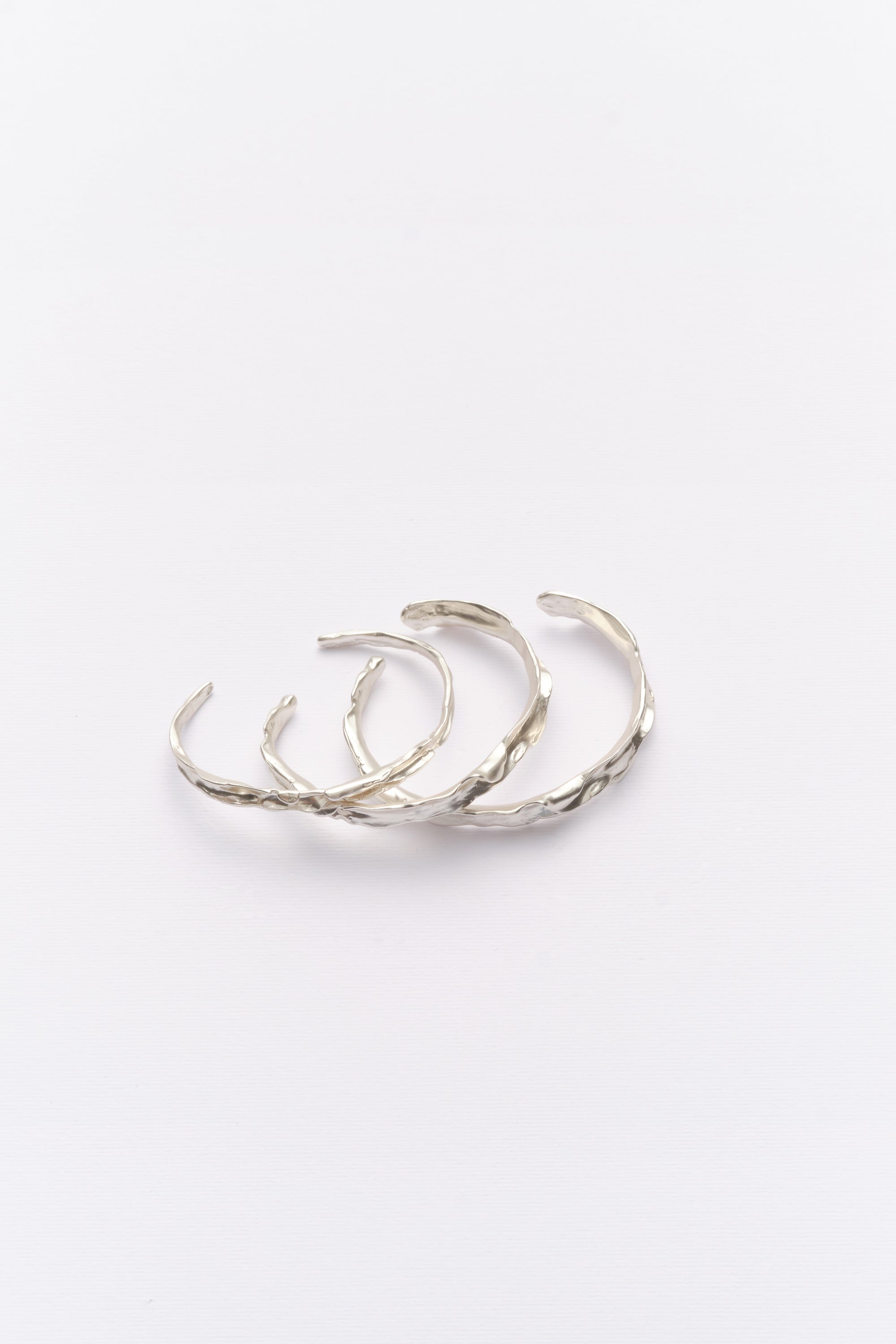 Stacked silver textured organic cuff bracelets flat lay