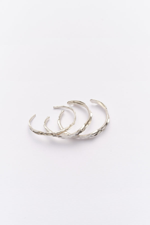 Stacked silver textured organic cuff bracelets flat lay