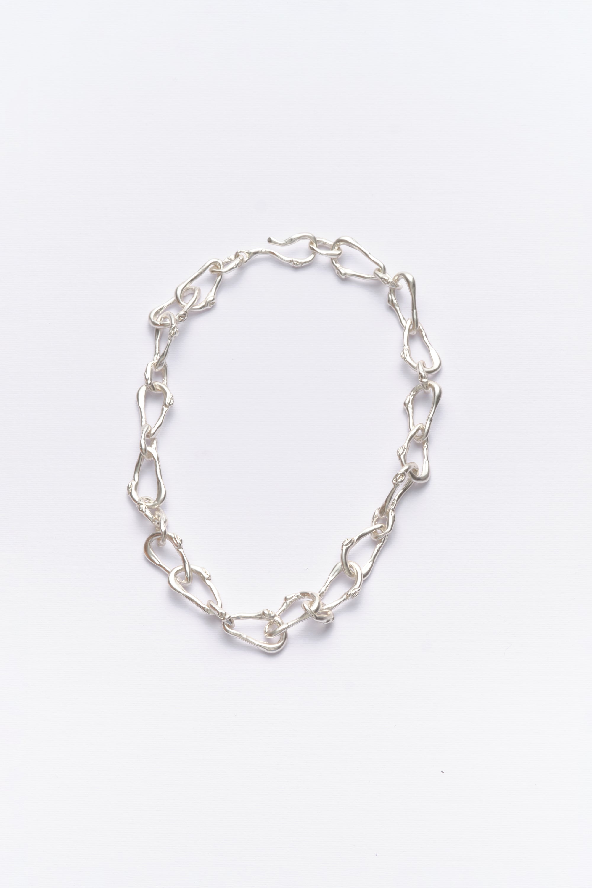 A silver-colored chain necklace with a unique link design, displayed against a white background.