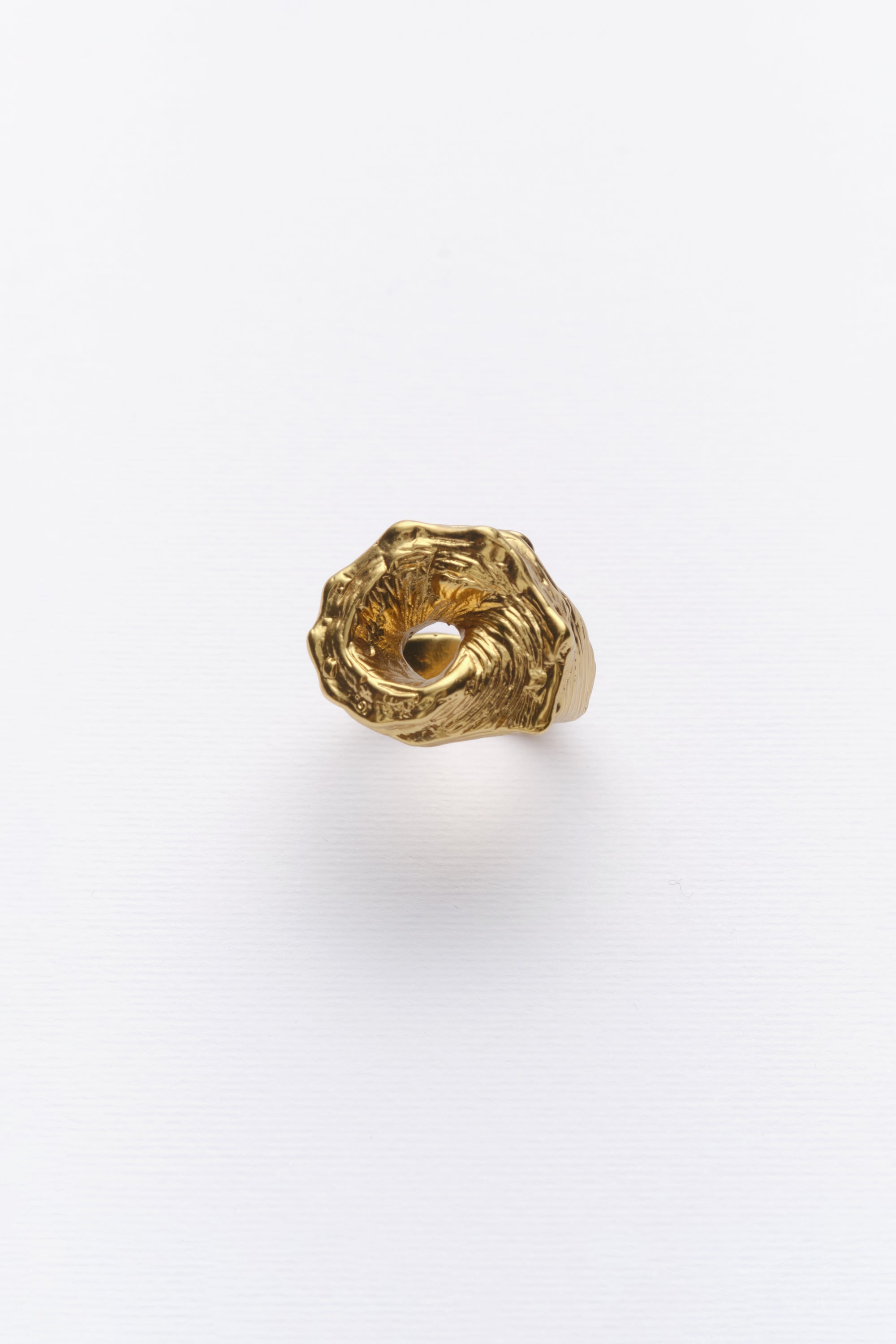A gold-colored ring with a textured design, inspired by the shape of a conch shell.