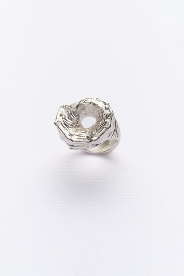 A silver-colored ring with a textured design, inspired by the shape of a conch shell.
