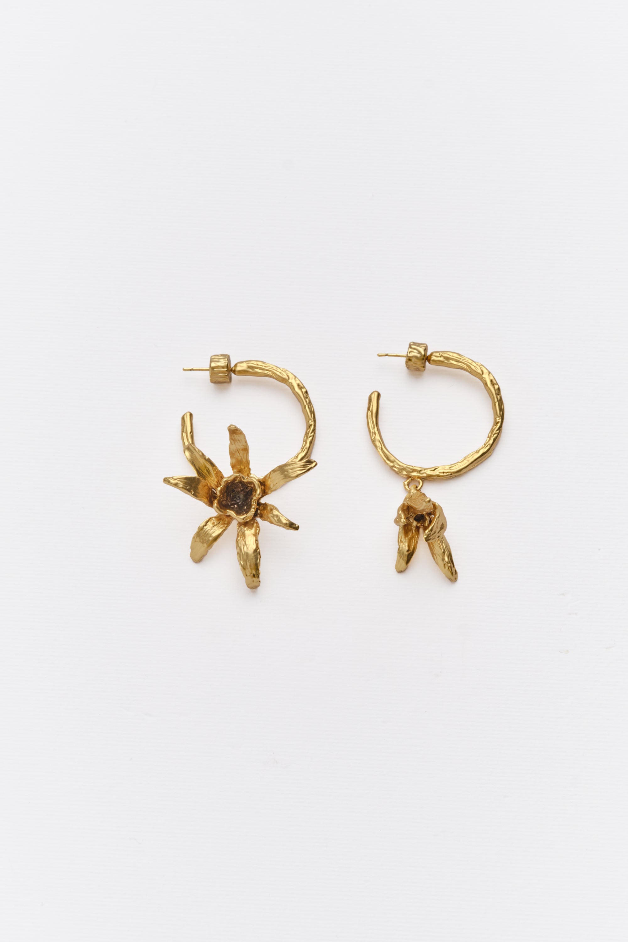 A pair of gold-colored hoop earrings with a floral design on a white background