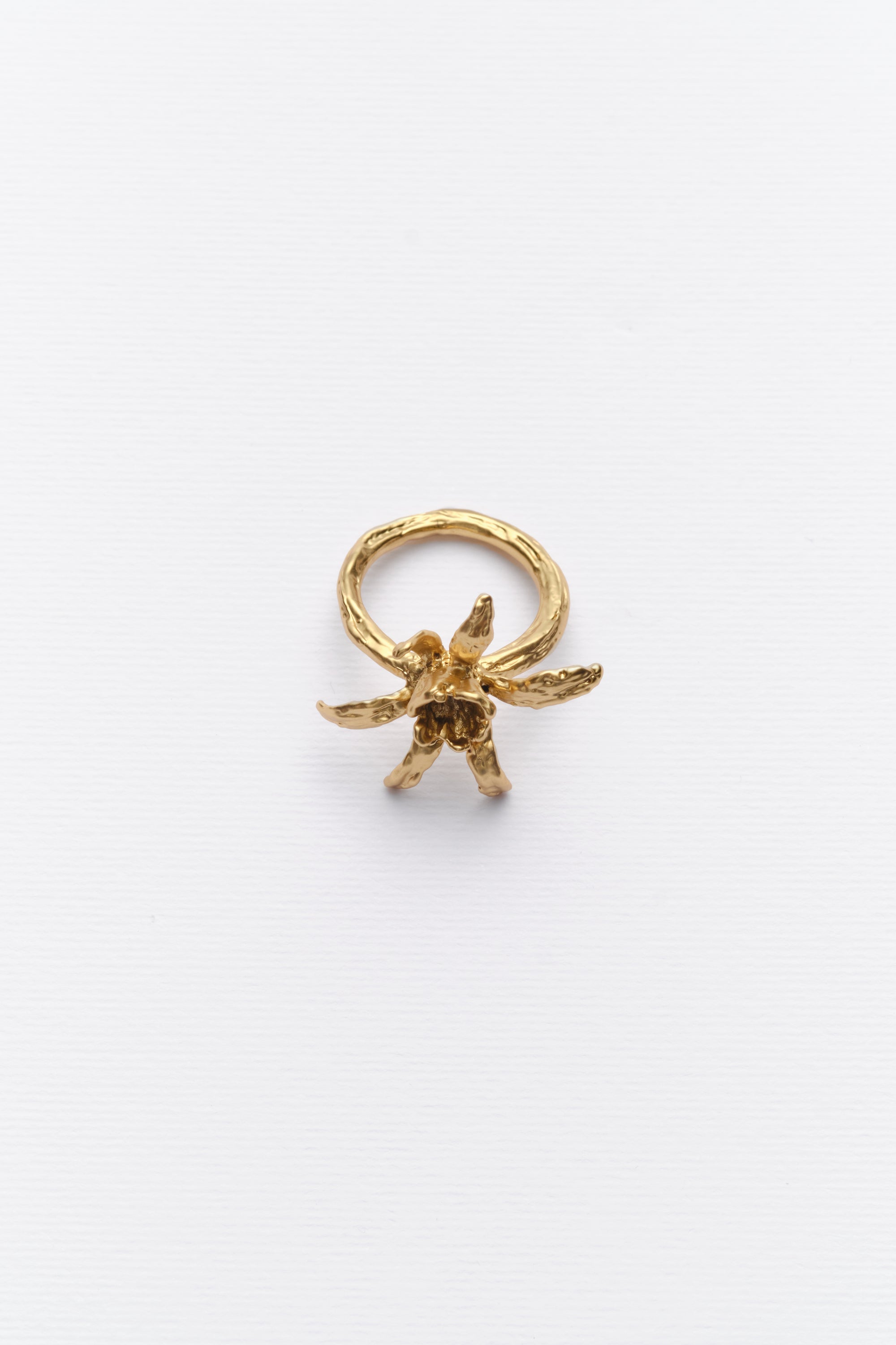A gold-colored ring with an iris flower design on a white background.