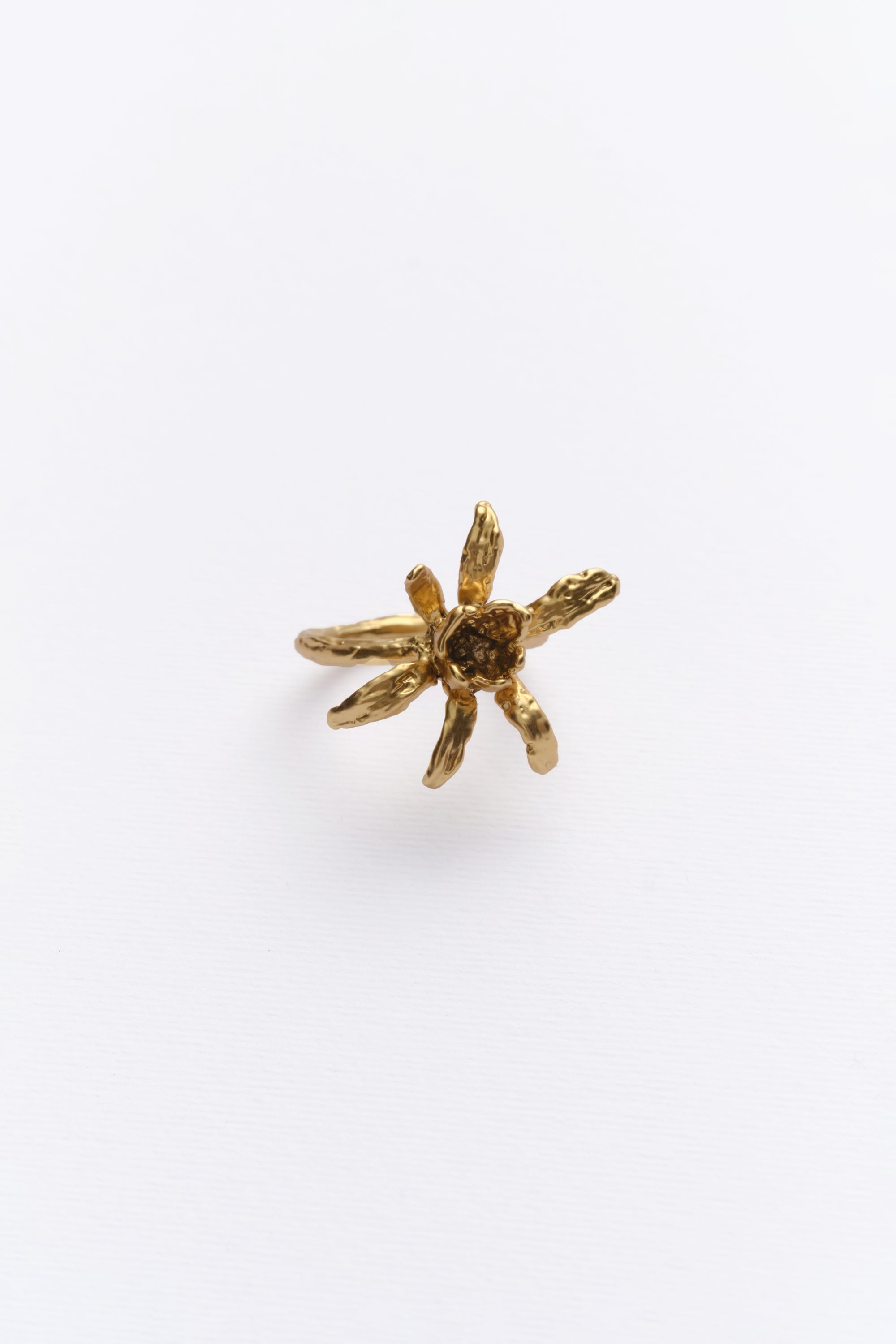 A gold-colored ring with an iris flower design on a white background.
