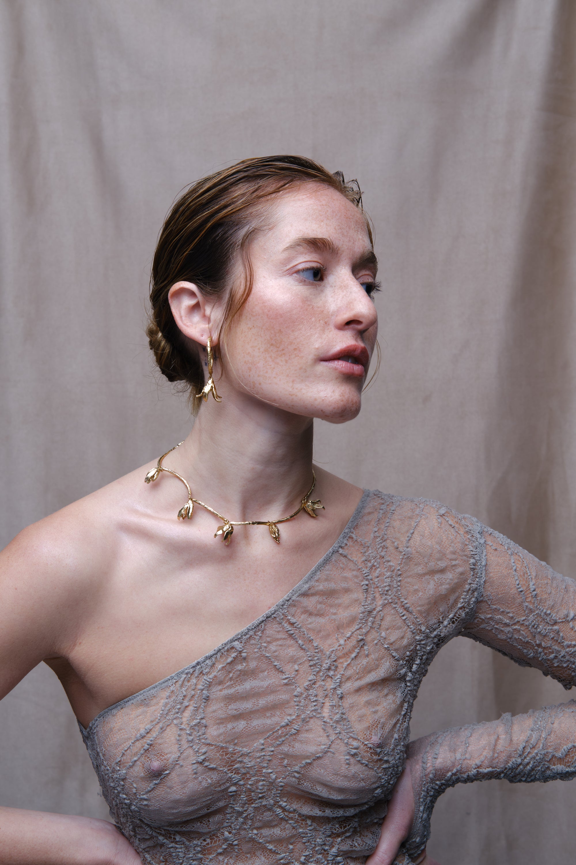 Model wearing gold sculptural flower necklace and drop earrings portrait