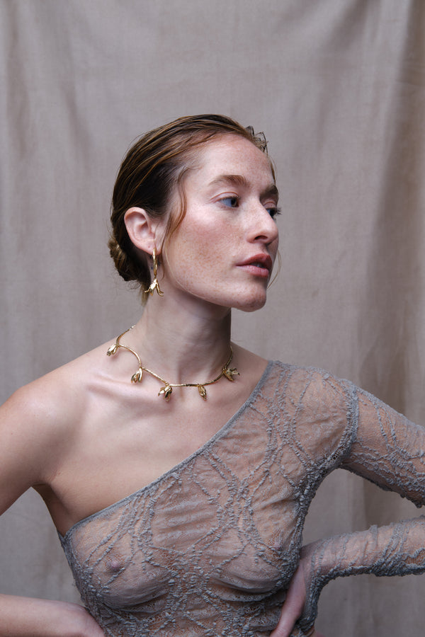 Model wearing gold sculptural flower necklace and drop earrings portrait