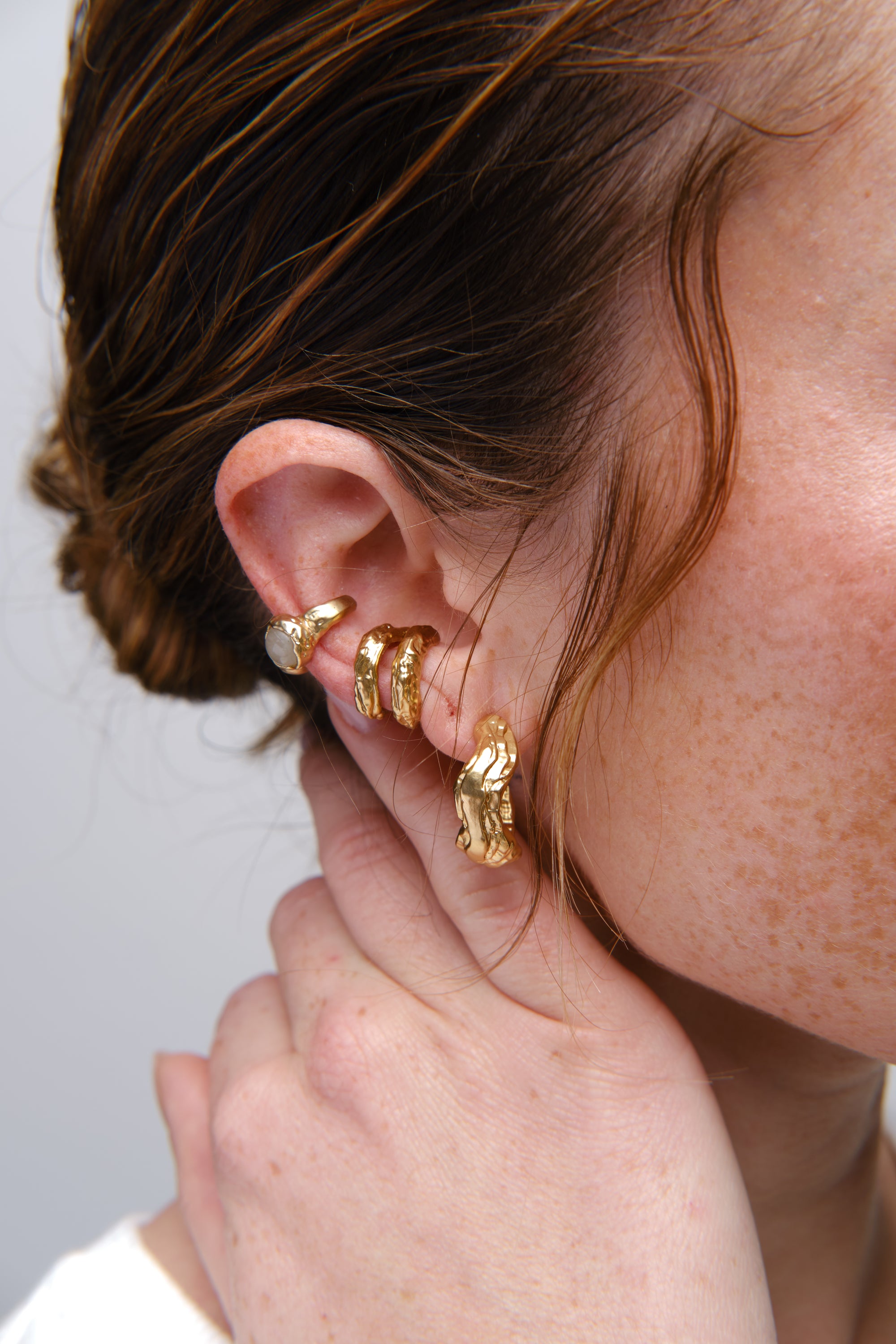 Gold sculptural ear stack earrings close-up on model