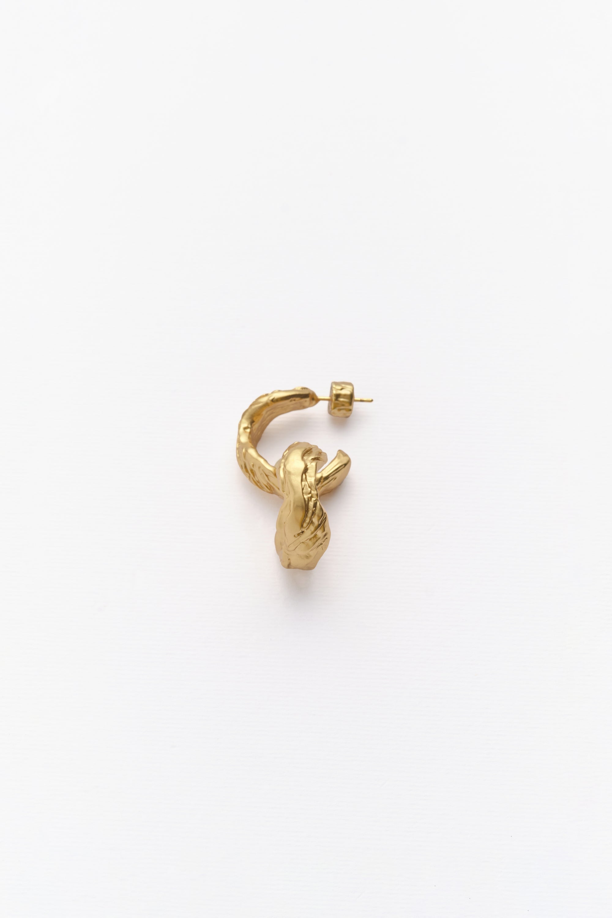 A single gold-colored hoop earring with an irregular texture, displayed against a white background.