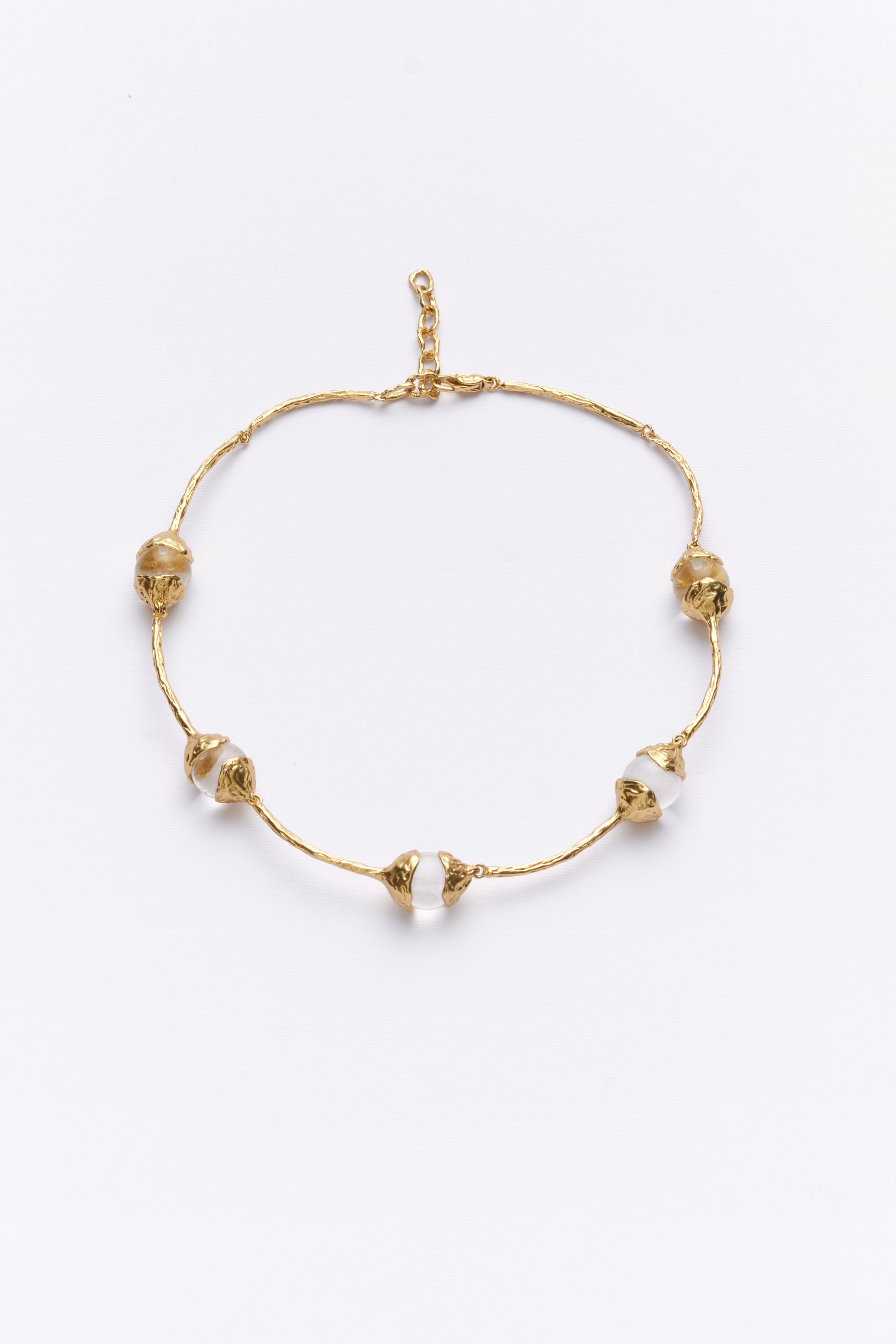 A gold-colored necklace with glass beads arranged in a pattern along the length of the necklace.