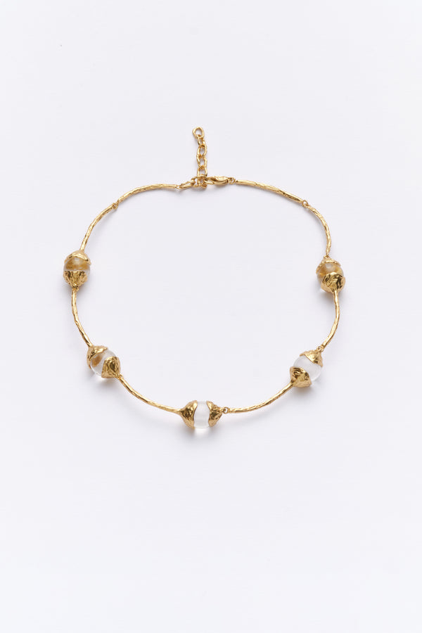 A gold-colored necklace with glass beads arranged in a pattern along the length of the necklace.