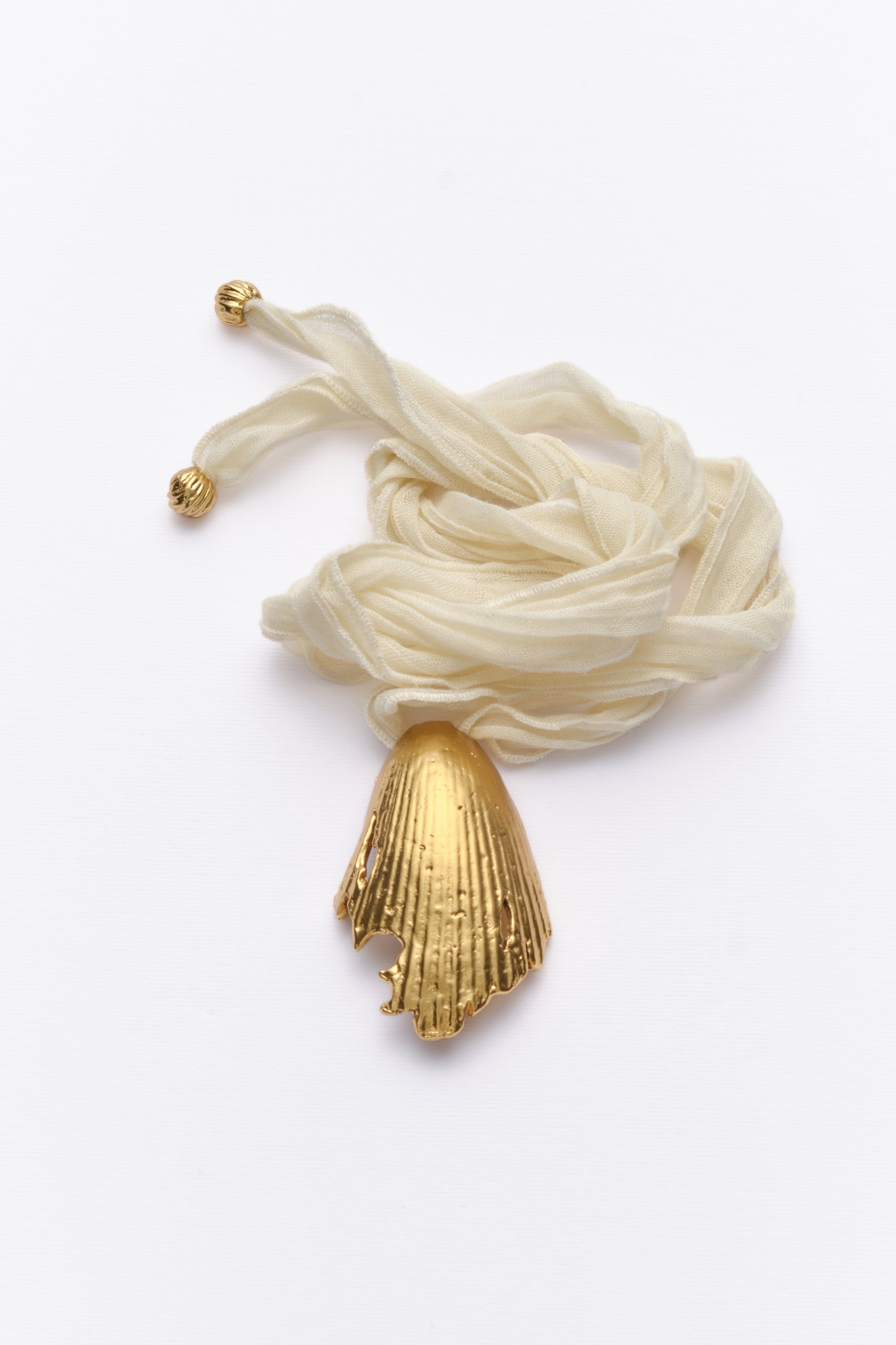 Gold textured shell pendant necklace with ivory silk cord flat lay