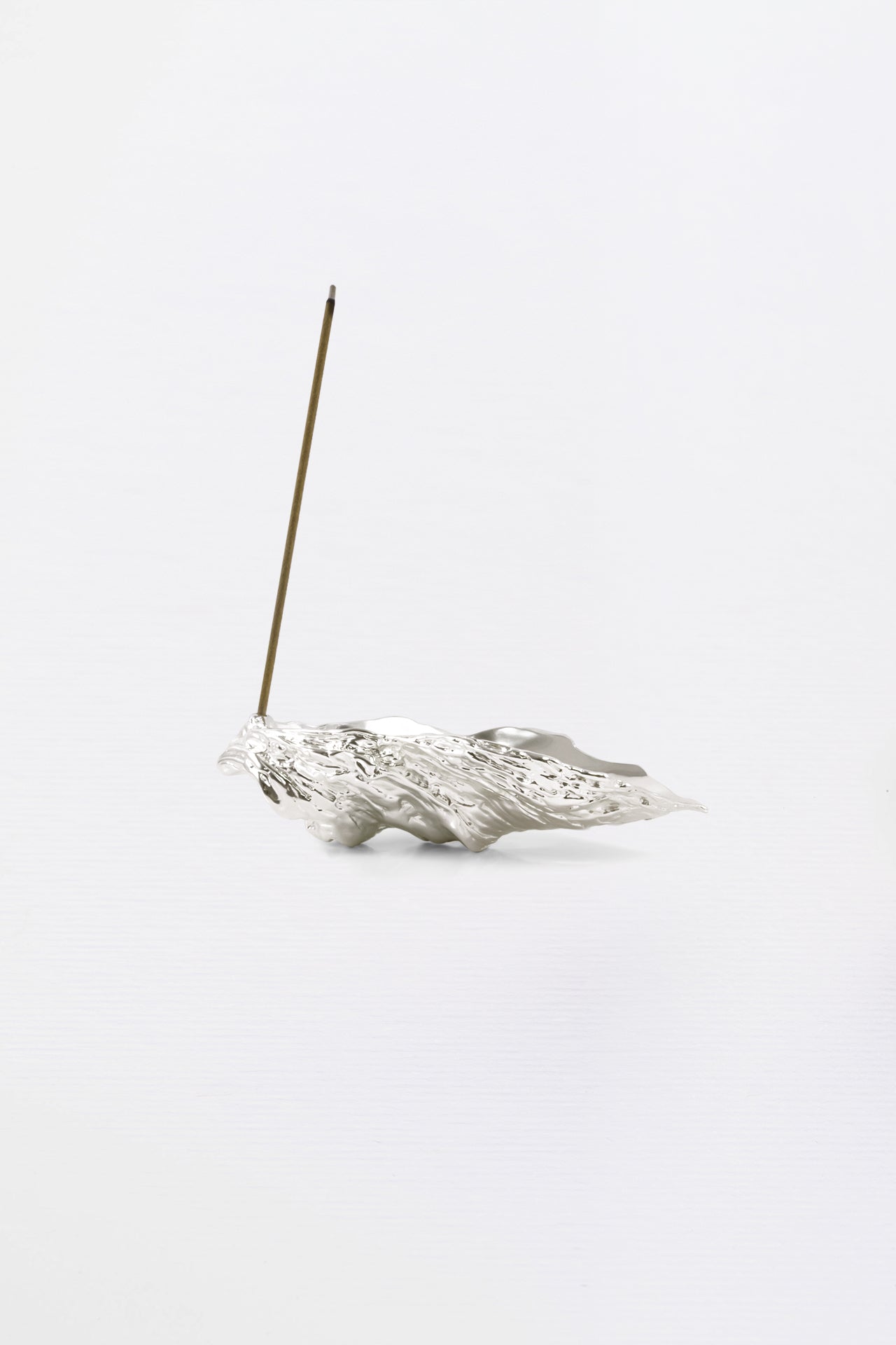 Silver incense holder with a single incense stick on a white background