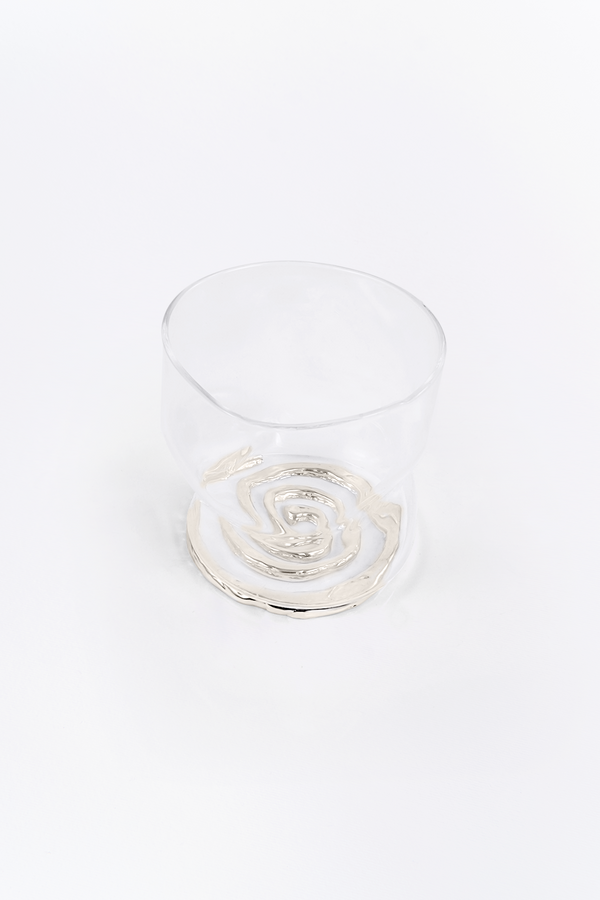 Clear glass rcup withe the spiral coaster on a white background
