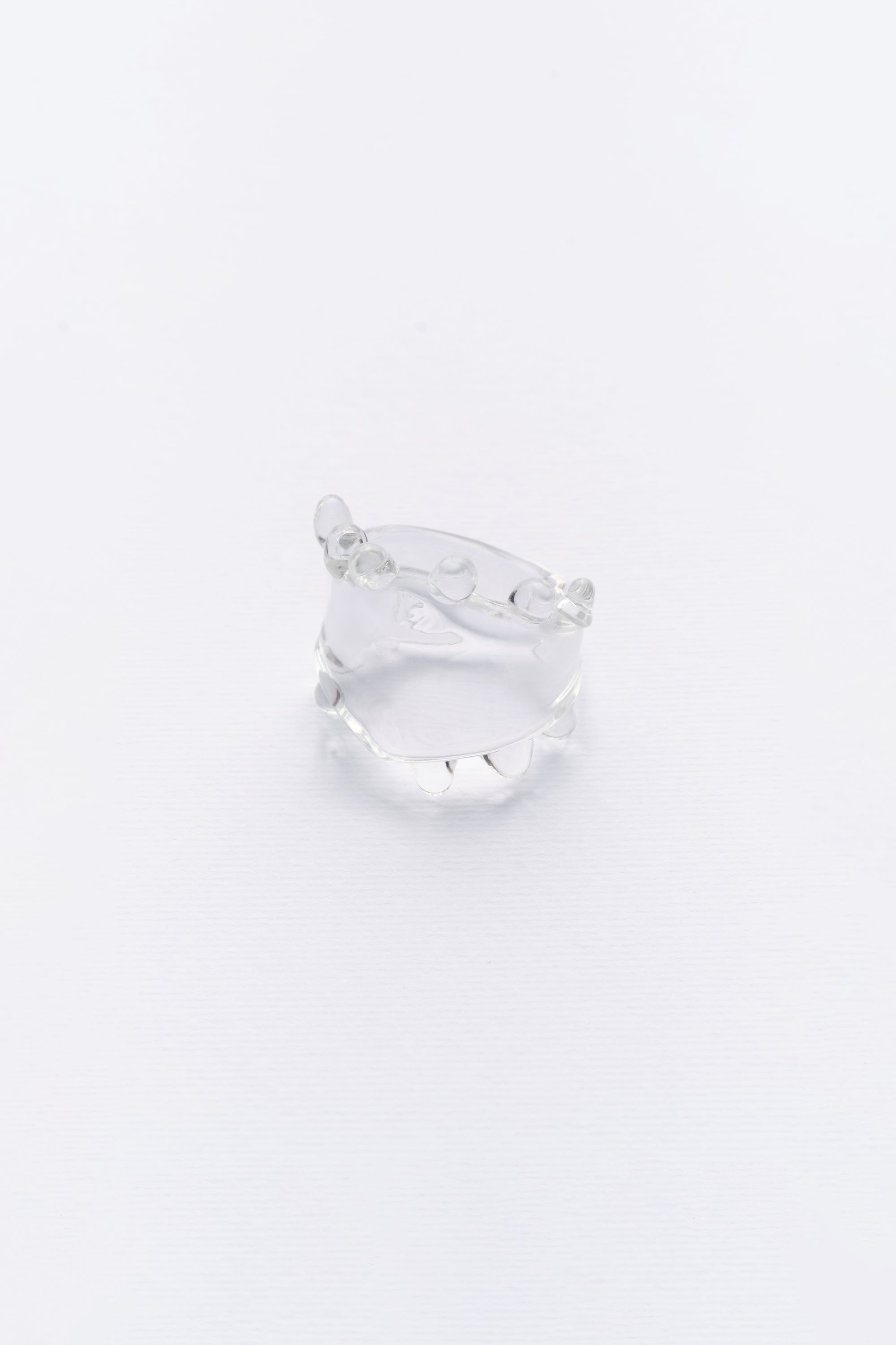 A clear glass ring with a smooth, sleek design, displayed against a white background.