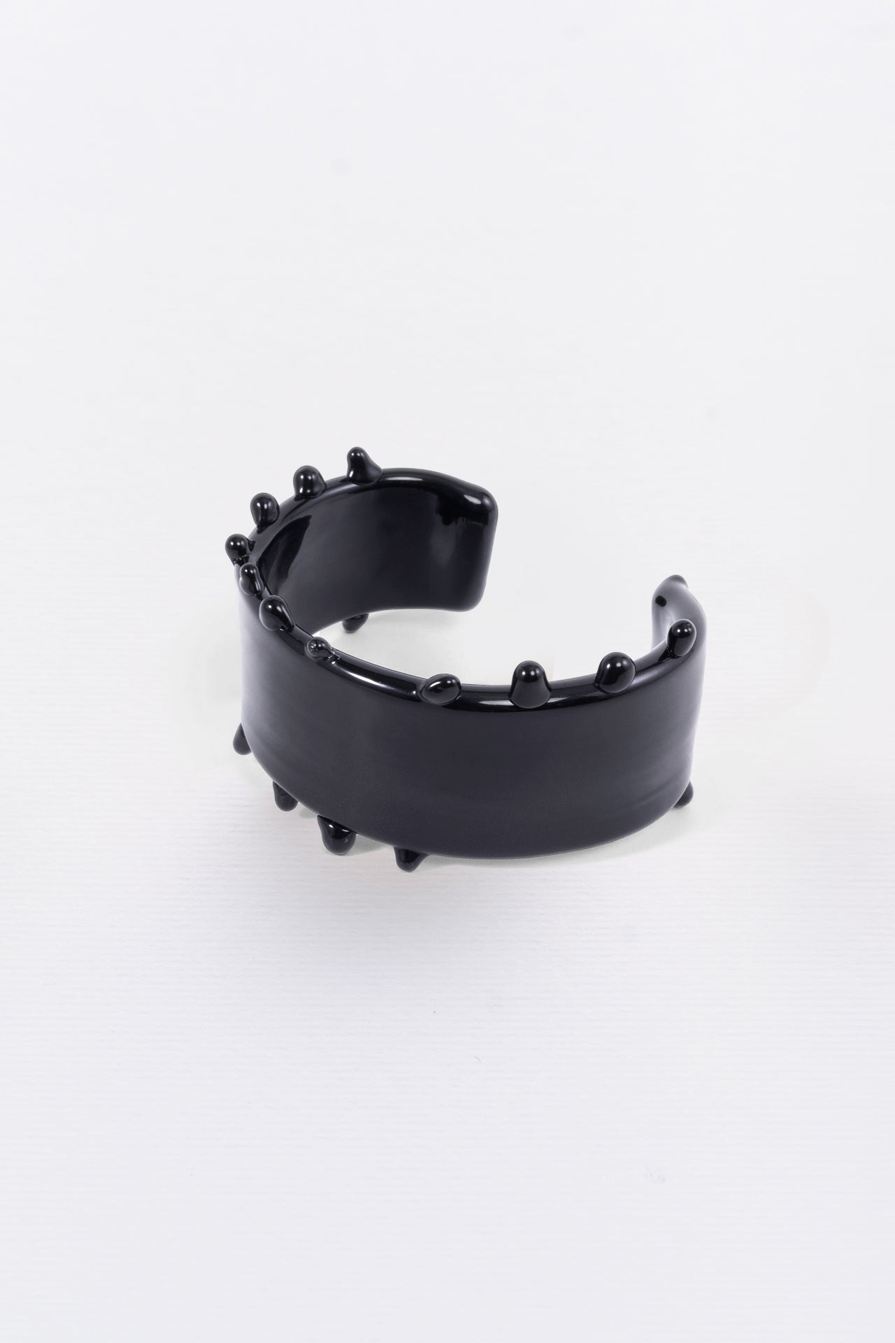 A black crystal cuff bracelet with a textured surface, displayed against a white background.