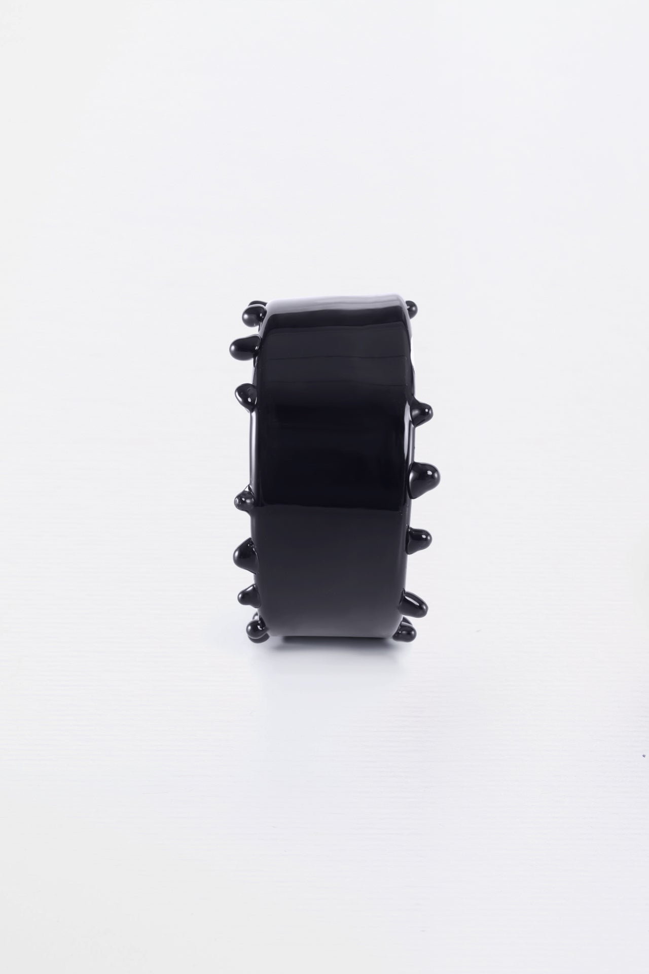 A black crystal cuff bracelet with a textured surface, displayed against a white background.