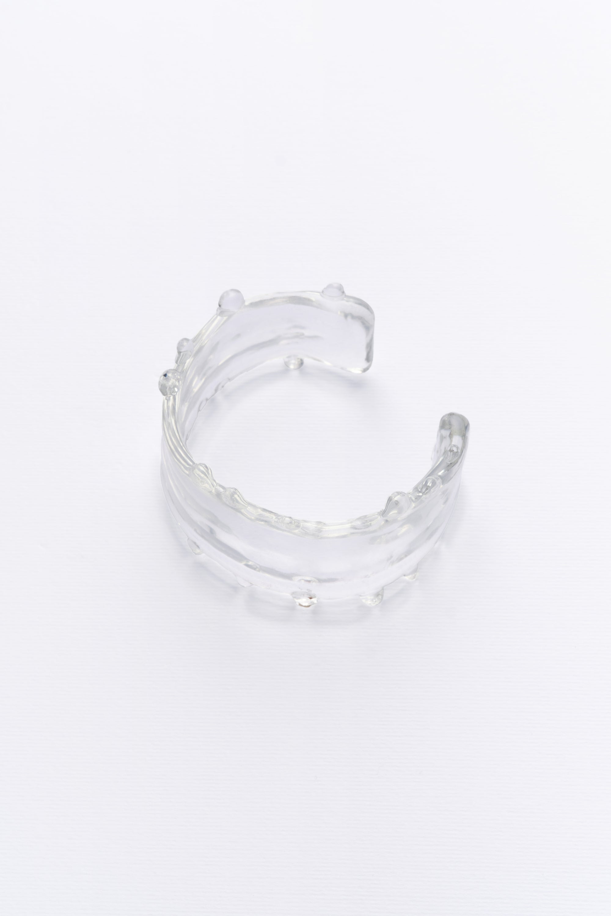 Side view of the clear crystal cuff bracelet with a smooth, elegant design, capturing the gentle flow of water.
