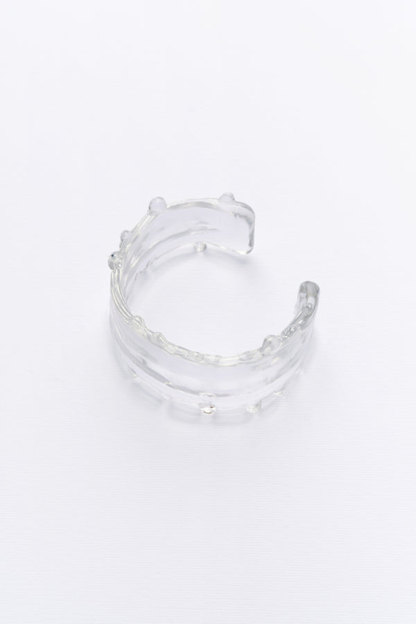 Side view of the clear crystal cuff bracelet with a smooth, elegant design, capturing the gentle flow of water.