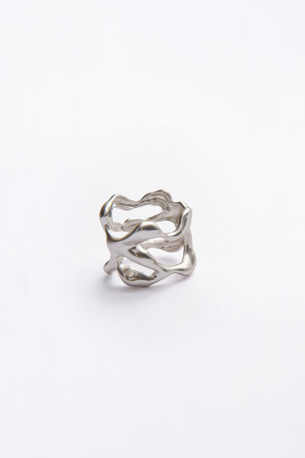 Modern sculptural silver napkin ring with organic textured design on white background