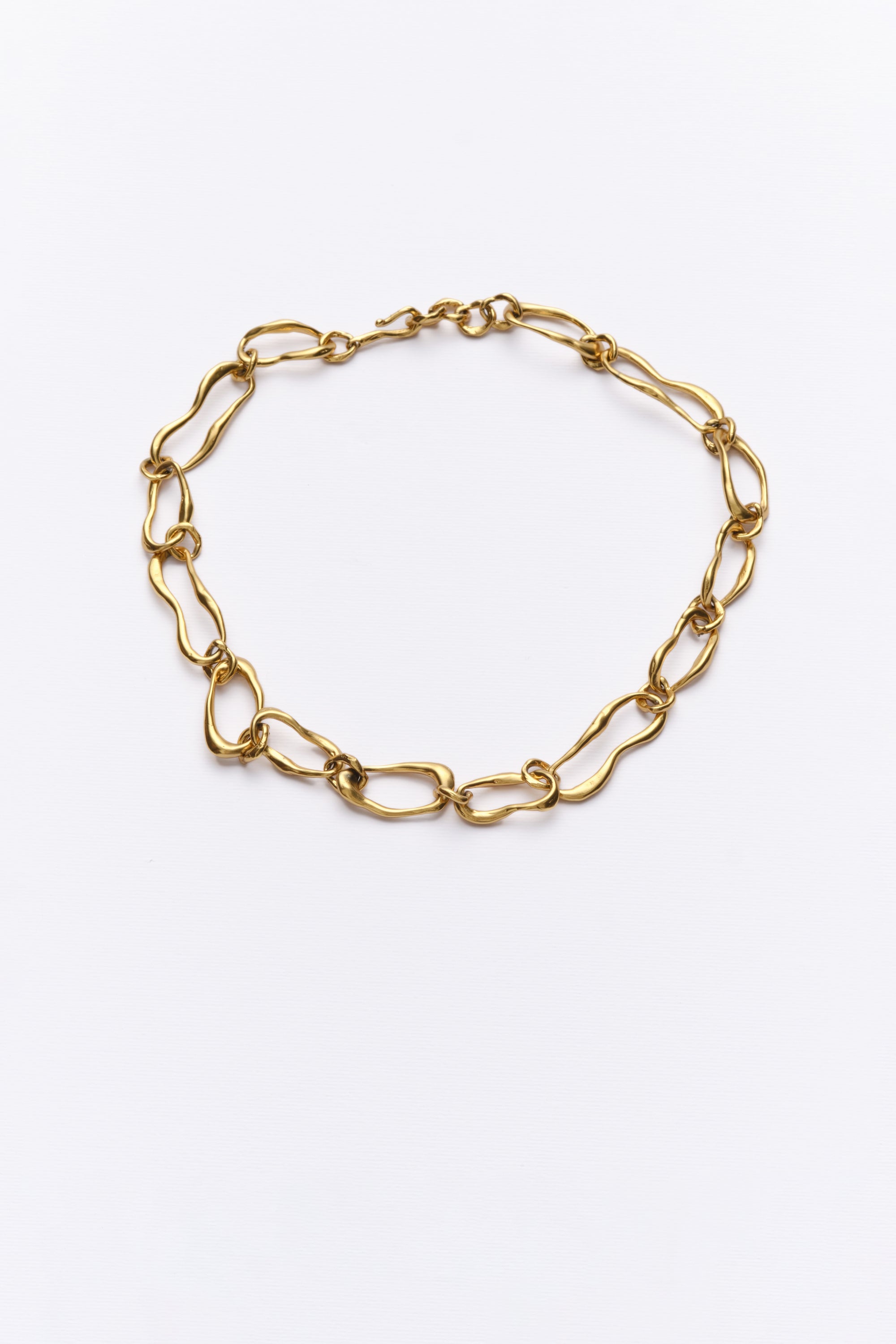 A gold-colored chain necklace with organic-shaped links on a white background.