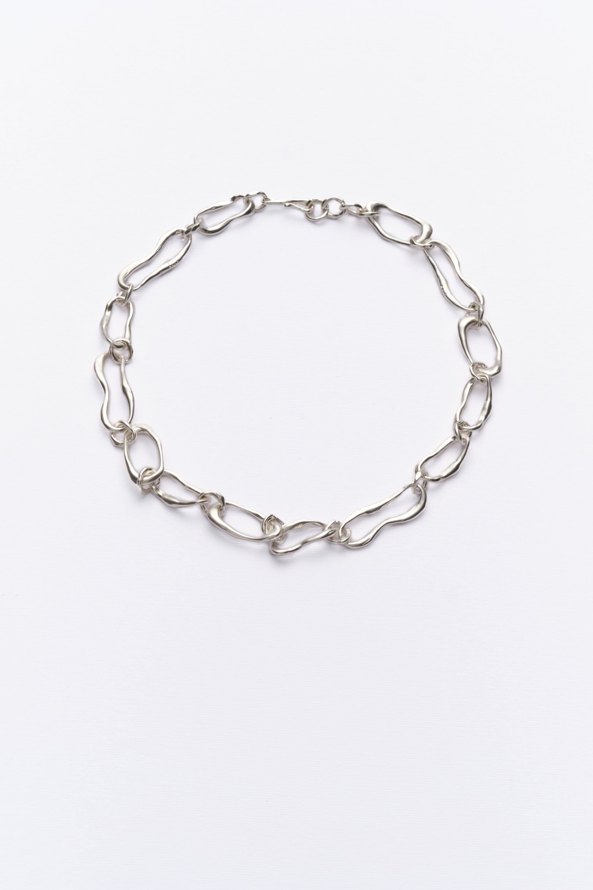 A silver-colored chain necklace with organic-shaped links, displayed against a white background.