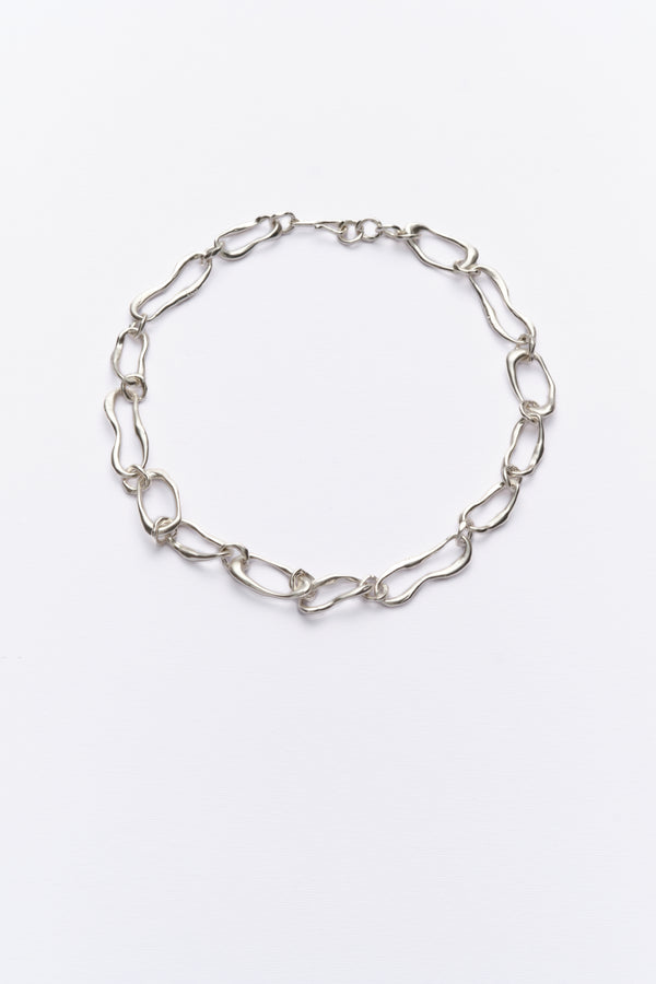 A silver-colored chain necklace with organic-shaped links, displayed against a white background.