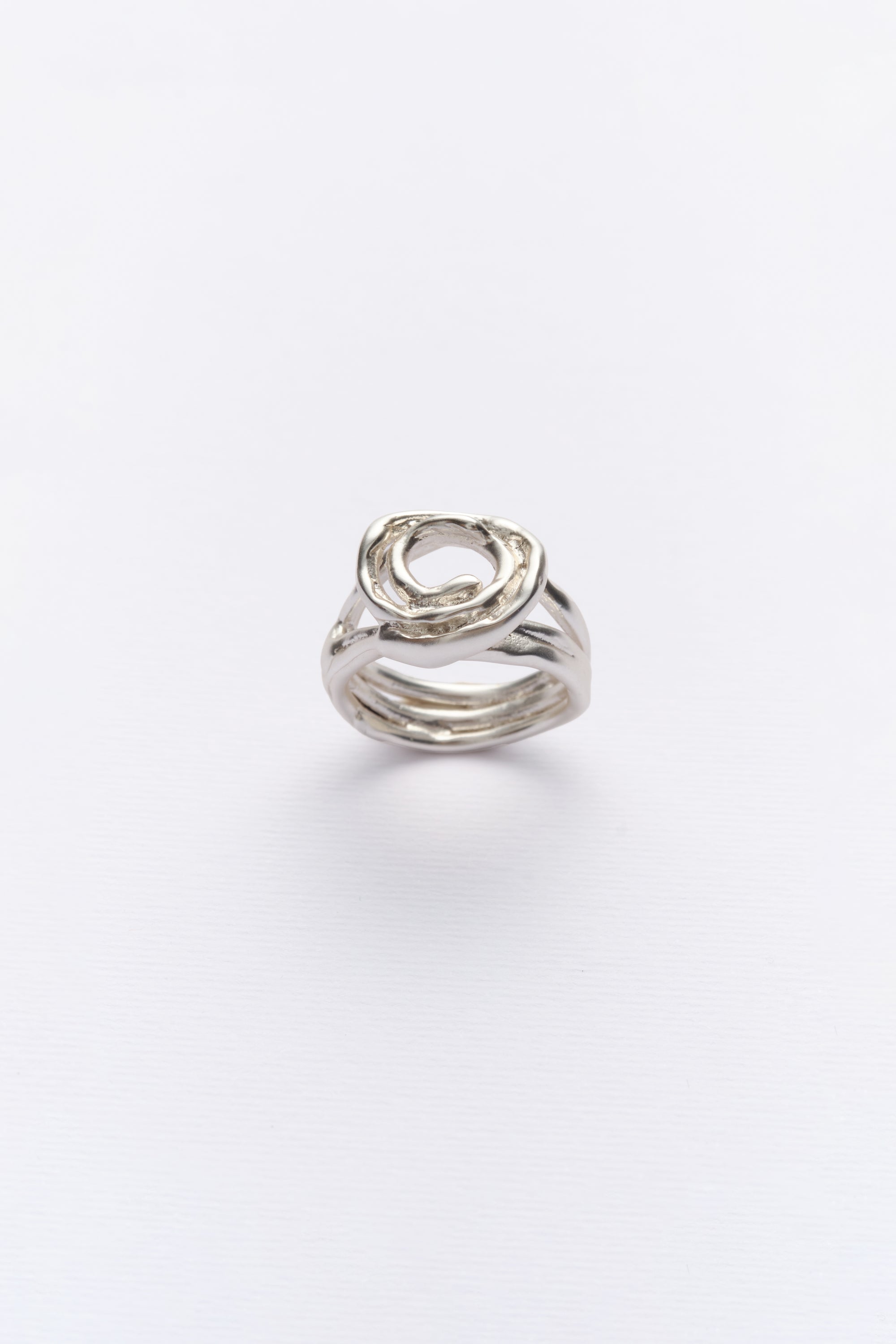 A silver ring with a unique design, featuring multiple bands twisted together, displayed against a white background.