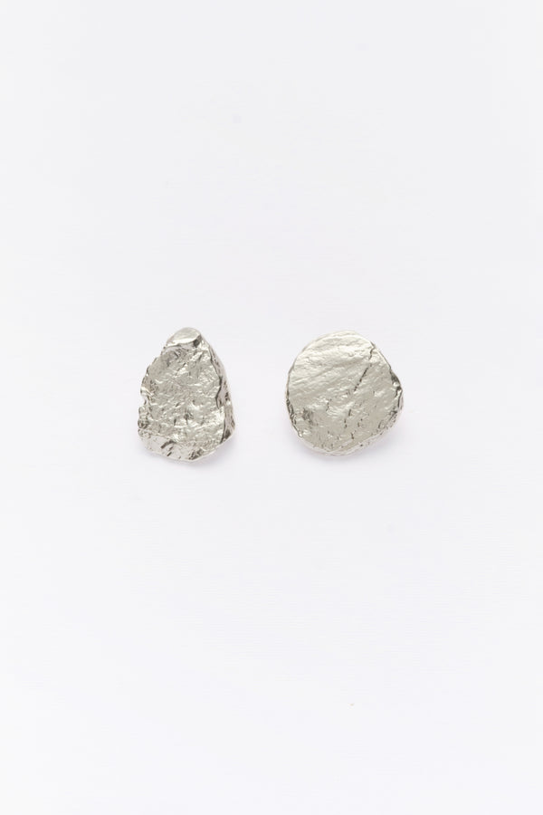 A pair of silver, asymmetric earrings with a textured surface on a white background.