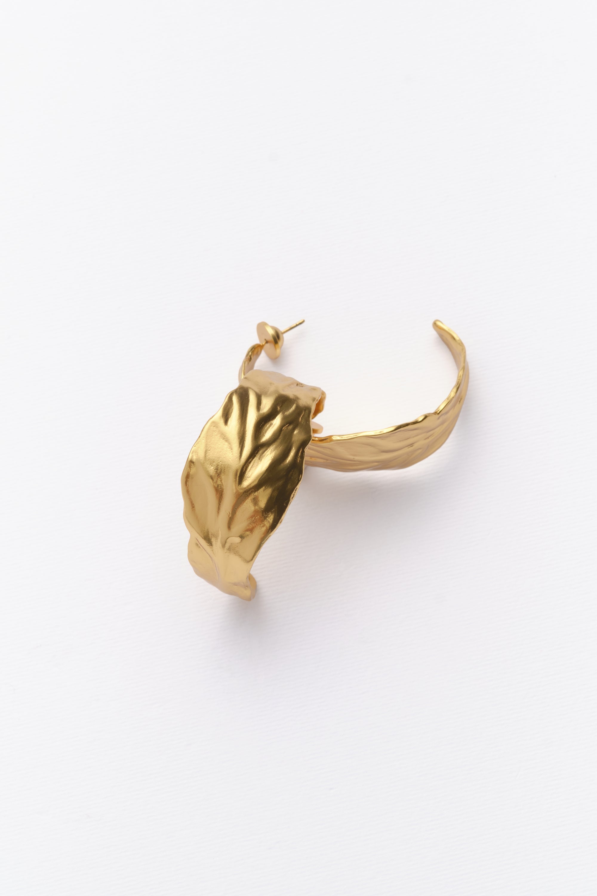 A pair of gold-colored hoop earrings with a leaf texture on a white background.