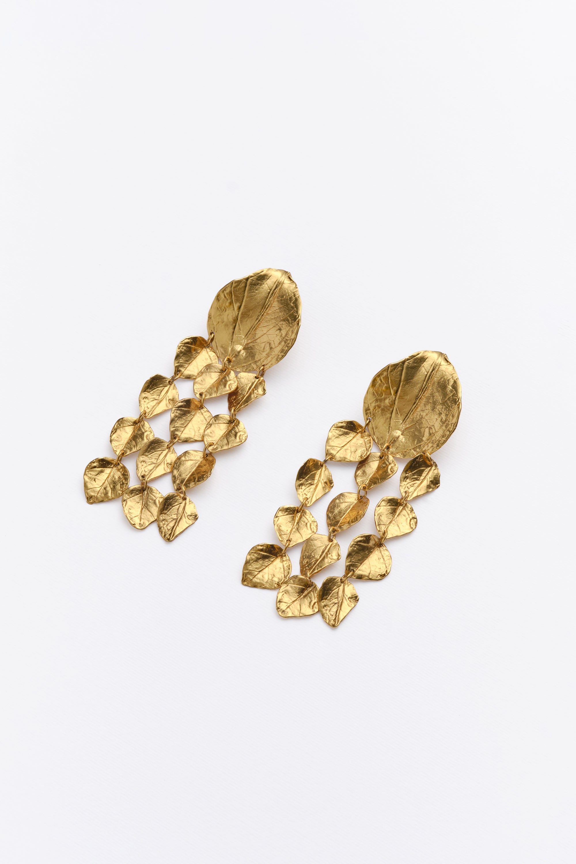 Angled view of gold textured leaf chandelier earrings