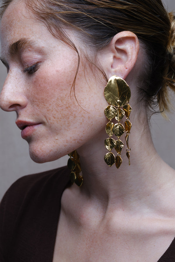 Gold textured leaf chandelier earrings worn on model