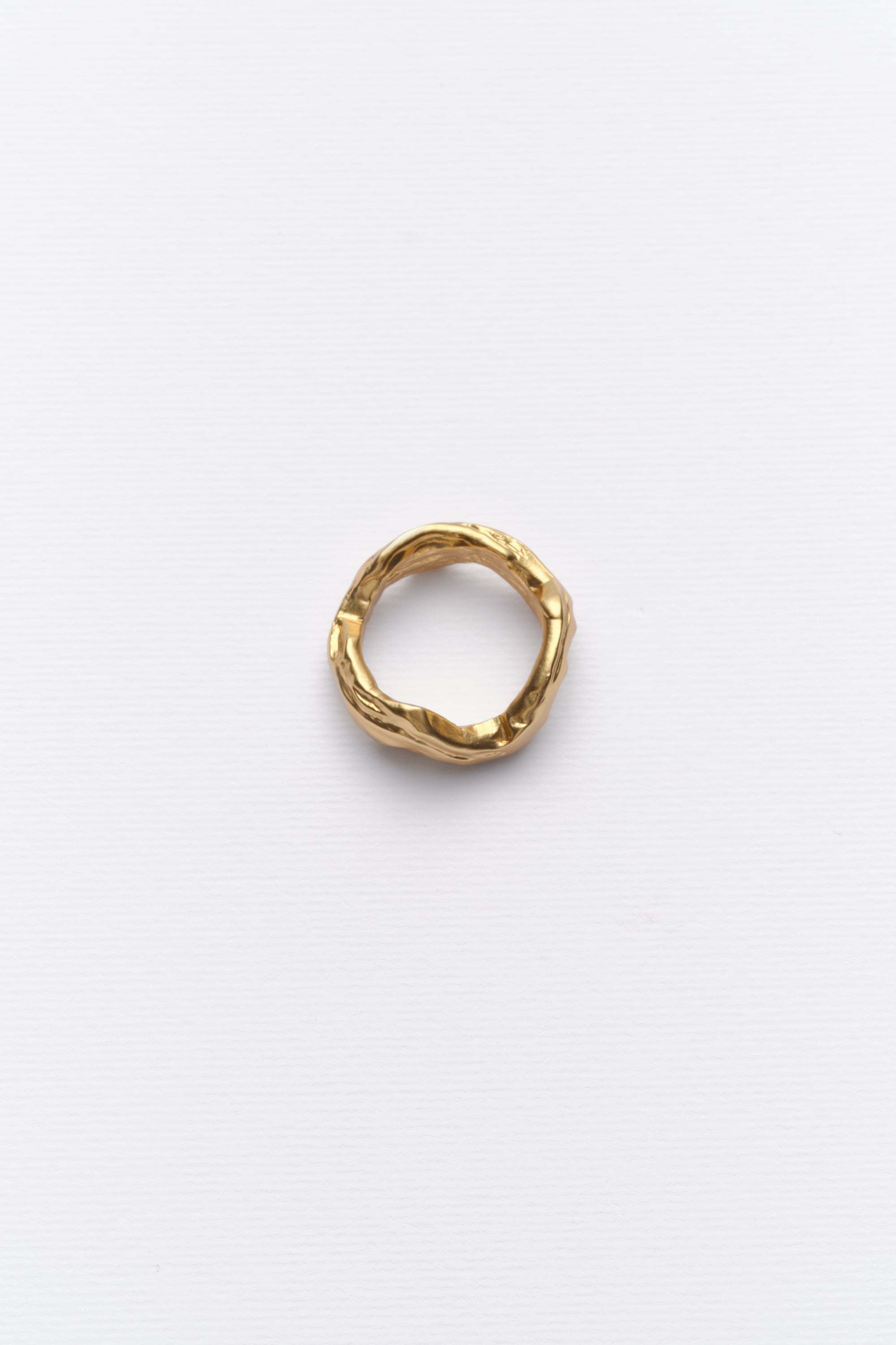 Minimalist textured gold ring displayed on clean white background