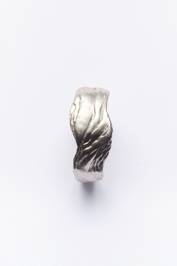 A silver statement cuff bracelet with textured design, displayed against a white background