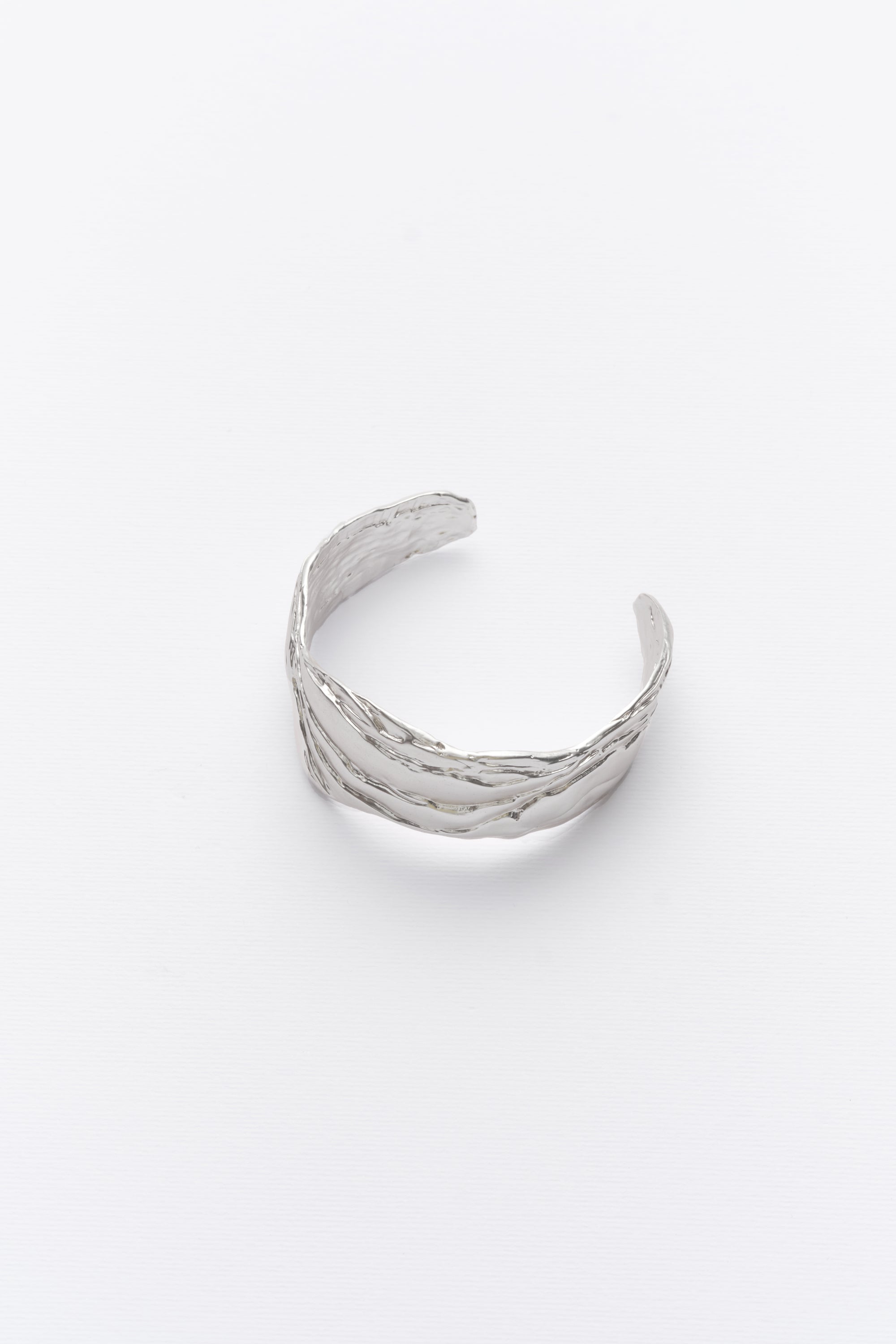 A silver statement cuff bracelet with textured design, displayed against a white background