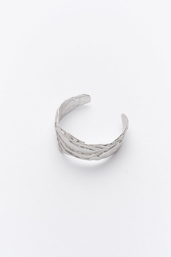 A silver statement cuff bracelet with textured design, displayed against a white background