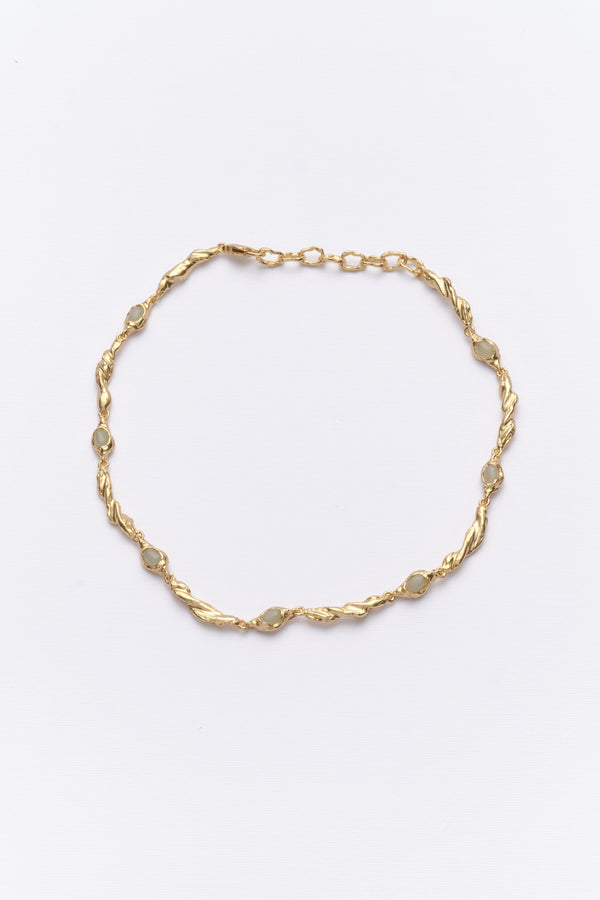 Gold organic link necklace with oval white gemstones flat lay