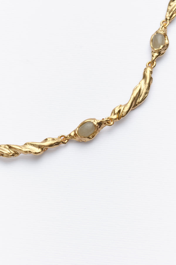 Close-up of gold organic link necklace with oval white gemstones