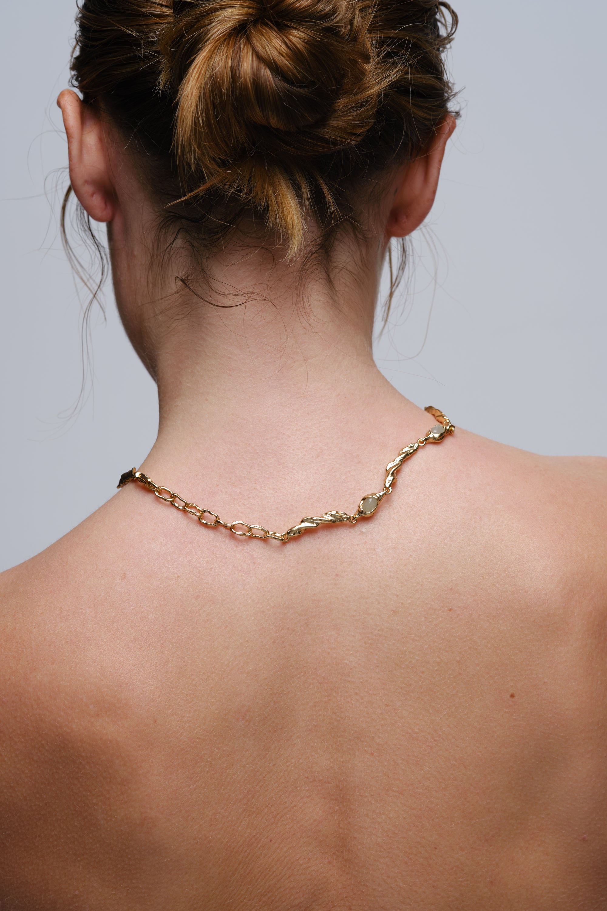 Back view of gold organic gemstone necklace worn on model